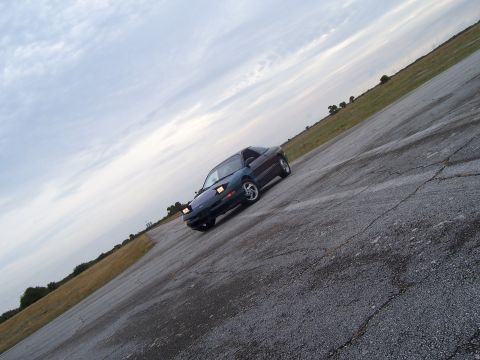 1994 Ford Probe - A 1994 Ford Probe coupe is parked on a cracked asphalt lot under a cloudy sky.