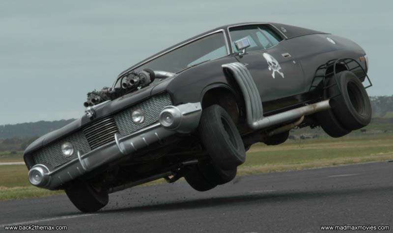 Black customized car on two wheels, with exposed engine, side pipes, and skull decal
