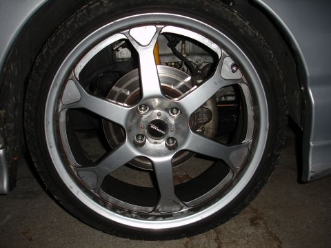 1995 Ford Taurus - Close-up of a silver aftermarket wheel and tire assembly, showing brake components behind the spokes.