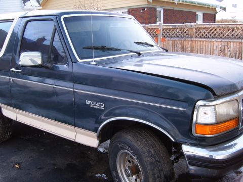 1993 Ford Bronco - The front quarter panel of a dark blue 1993 Ford Bronco shows its distinctive body style and tan lower trim.