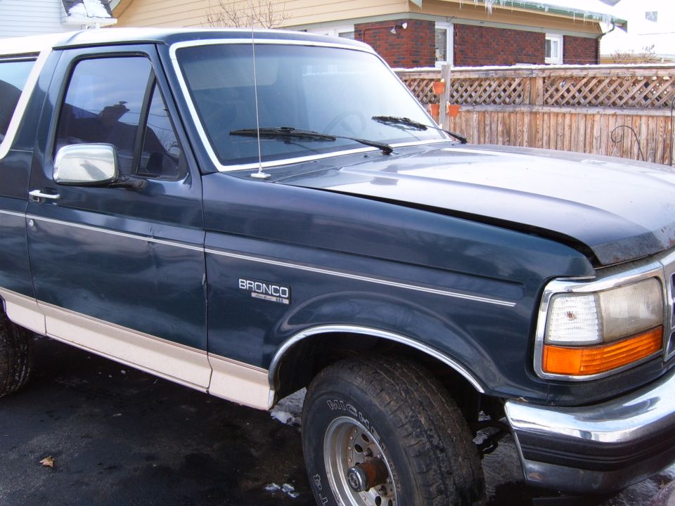 Dark blue 1993 Ford Bronco with tan lower trim, front fender and headlight visible