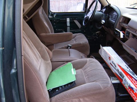 1993 Ford Bronco - Interior of a 1992 Ford Bronco, showing seats, dashboard, and steering wheel. A green folder and a tool box are visible.
