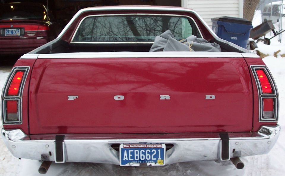 Red Ford Ranchero from behind, parked in snow. Another red car is visible in the background