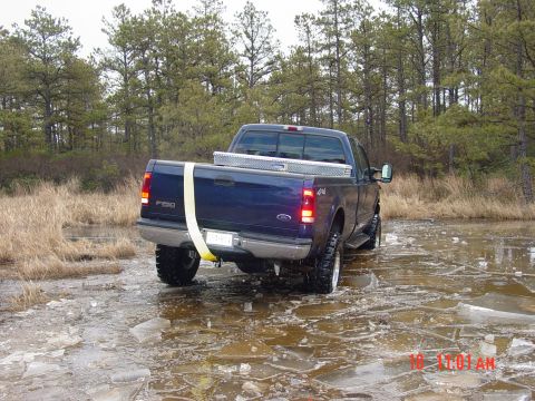 1995 Dodge 1500 - A blue Ford F-250 pickup truck navigates a partially frozen, watery terrain.