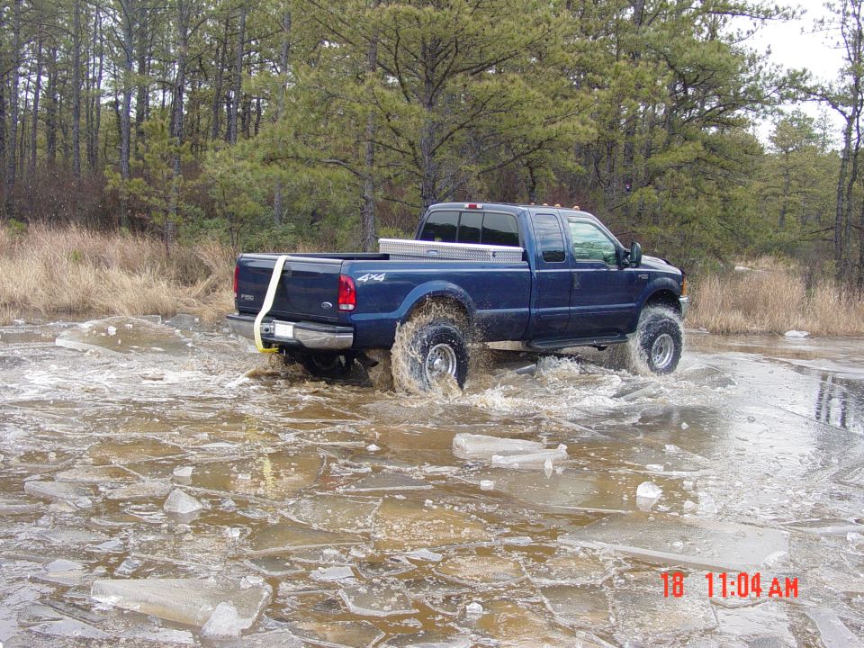 Blue pickup truck with 4x4 decal driving through icy water