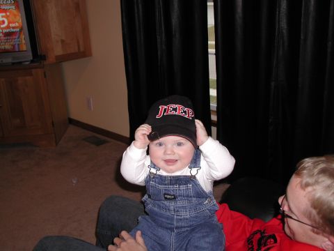 1998 Jeep TJ - A baby smiles while wearing a black baseball cap with the word "JEEP" on it.