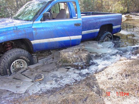 1995 Dodge 1500 - A blue pickup truck is stuck in a frozen, muddy area with large chunks of ice around its tires.