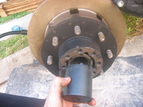 1989 Ford Bronco - Close-up view of a vehicle's wheel hub assembly, with a hand holding a socket wrench near the center nut.