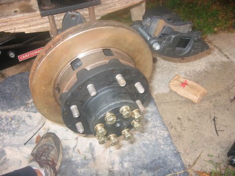 1989 Ford Bronco - A close-up view of a vehicle's brake rotor and caliper assembly, with a Craftsman jack visible in the background.