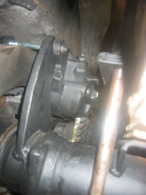 1989 Ford Bronco - Underside view of a vehicle's axle and brake components, showing the caliper and mounting bracket.