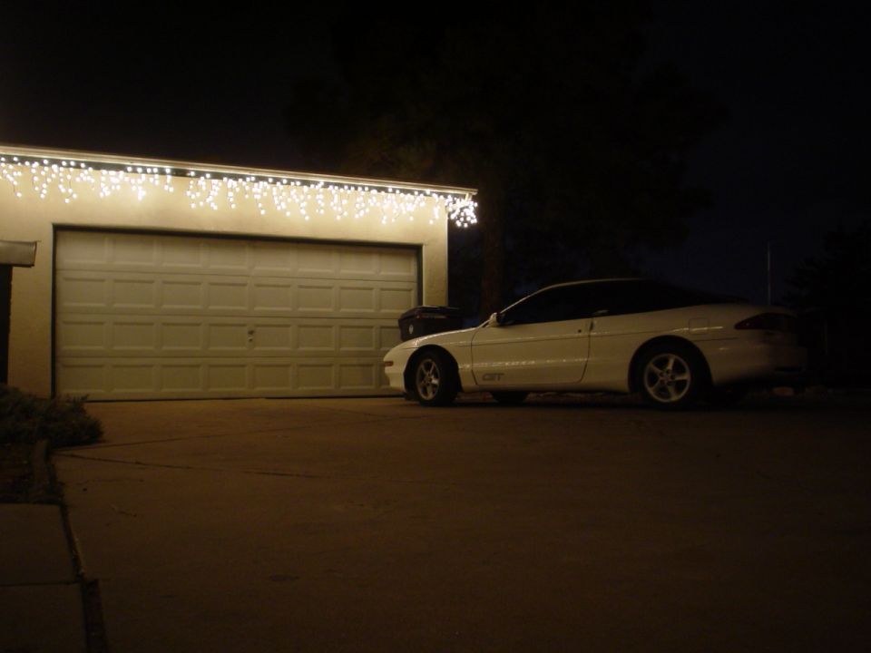 1993 Ford Probe side view, white coupe parked in front of garage at night