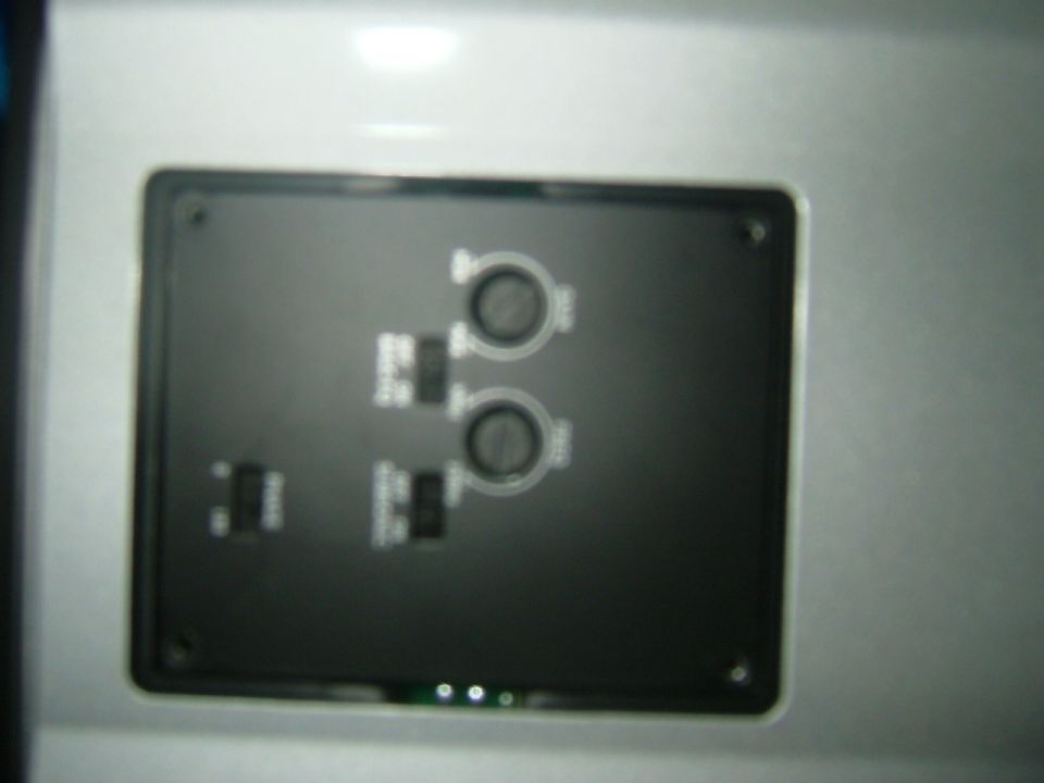 Close-up of a black aftermarket control panel with two circular knobs and several toggle switches