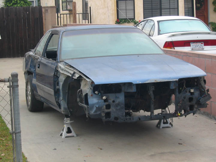 Blue 1989 Mazda MX-6 coupe, front end removed, on jack stands