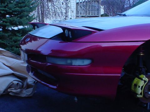 1993 Ford Probe - The front end of a red 1993 Ford Probe is shown with its pop-up headlights, one of which is partially open.