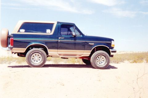 1995 Ford Bronco - This Ford Bronco is parked in a dry, outdoor landscape under a clear blue sky.