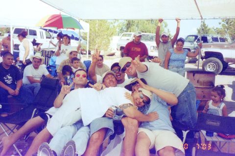 1995 Ford Bronco - A group of friends and family gather for a photo, with several vehicles visible in the background under a sunny sky.