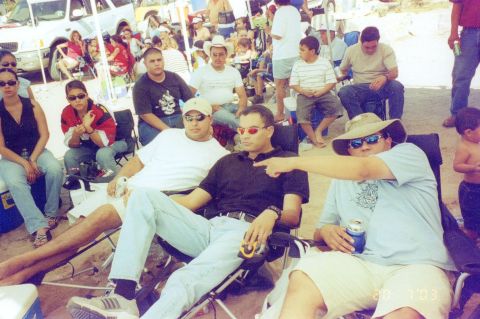 1995 Ford Bronco - People relax outdoors under a canopy, with some pointing in different directions.