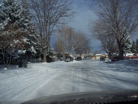 1972 Ford Ranchero - A quiet, snow-covered street in a residential neighborhood under a cloudy sky.