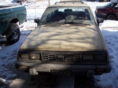 1972 Ford Ranchero - A tan station wagon is parked in the snow next to a green pickup truck, with another car visible in the background.