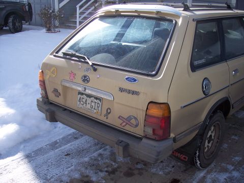 1972 Ford Ranchero - A tan 1979 Ford Ranchero is parked in a snowy driveway, showing its rear end with a license plate and stickers.