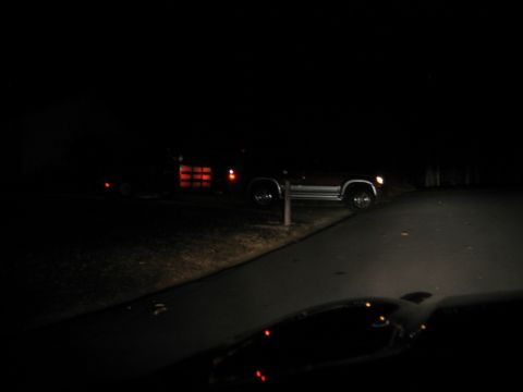 1985 Ford LTD Crown Victoria - A red SUV and trailer are parked on a dark road at night.