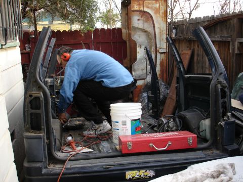 1993 Ford Taurus - A man works on the interior of a disassembled vehicle, surrounded by tools and parts.
