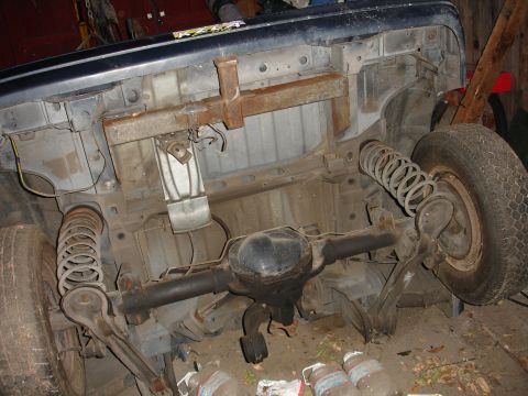 1993 Ford Taurus - The underside of a vehicle is shown, focusing on the rear axle, suspension components, and tires.
