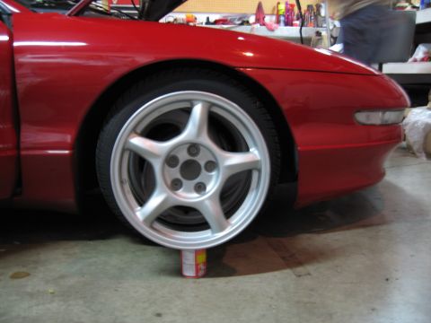 1994 Ford Probe - Front wheel of a red 1994 Ford Probe is being held up by a can.