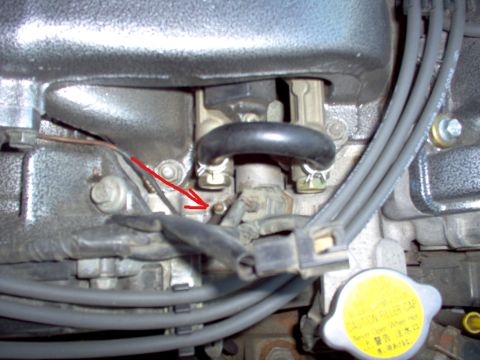 1994 Ford Probe - A close-up view of engine parts, highlighting a specific bolt with a red arrow indicator.