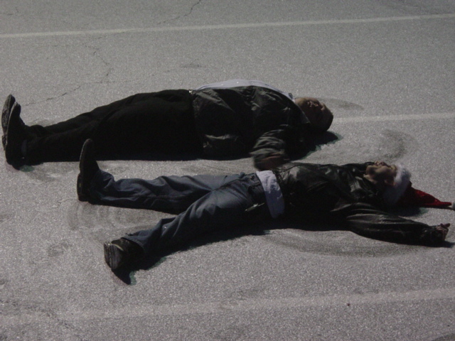 Two people are lying on the ground, one wearing a Santa hat. There's a Supermotors logo in the corner