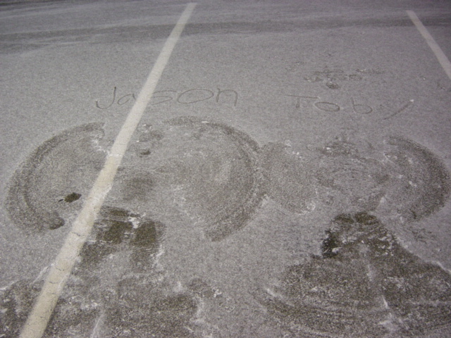 Snow angels with names written in the snow, on asphalt with a white line