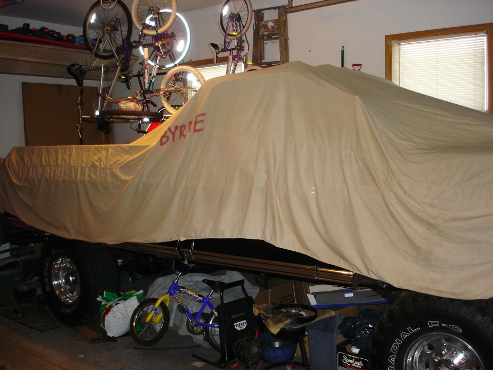 Vehicle covered with a tan tarp that has 'BYRIE' written on it in red