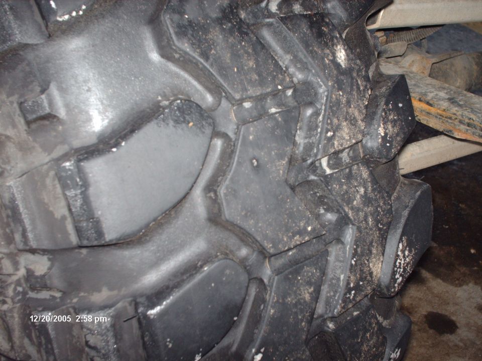 Close-up of aggressive off-road tire tread with mud and water on it. Date stamp visible