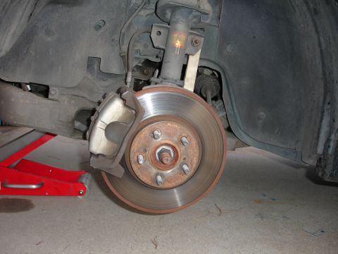 1995 Ford Taurus - A car's brake system, including the rotor and caliper, is shown with a red car jack visible.