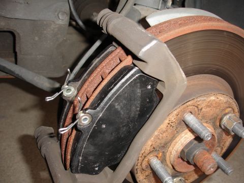 1995 Ford Taurus - A close-up view of a vehicle's brake caliper, rotor, and worn brake pads.