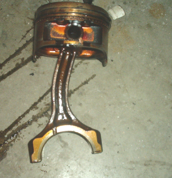 Piston and connecting rod assembly, likely from a damaged engine
