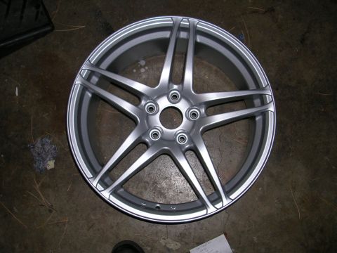 1996 Ford Probe - A single silver alloy wheel with five spokes is shown resting on a concrete surface.