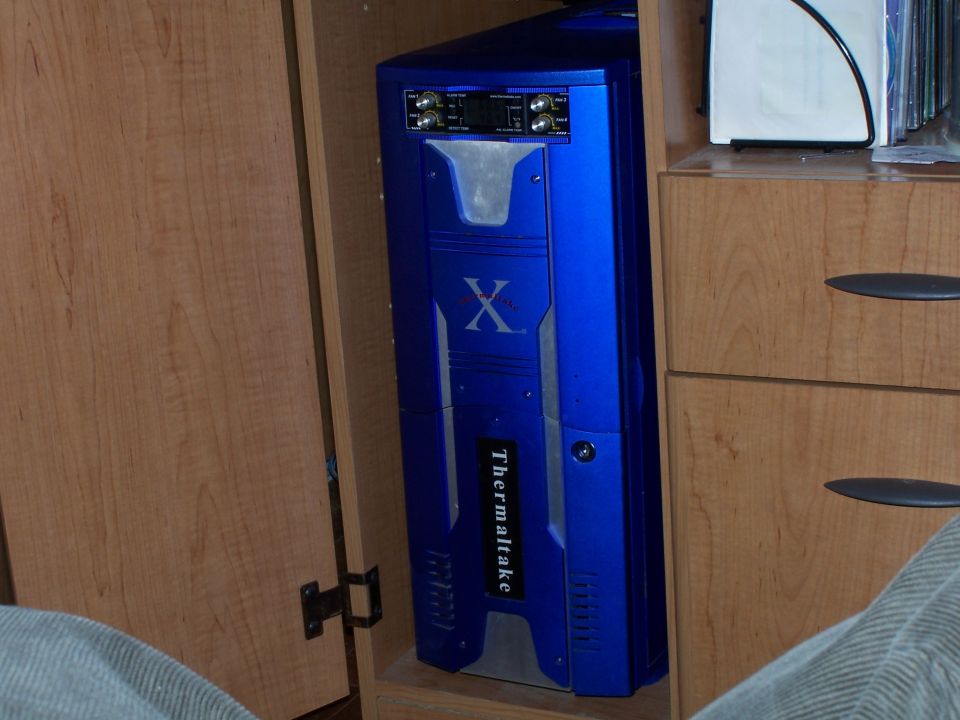 Blue Thermaltake computer tower with X logo inside a cabinet