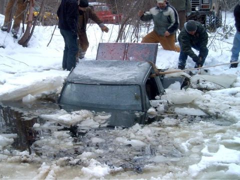 1995 Ford Bronco - A vehicle is submerged in icy water as several people attempt to extract it from the frozen predicament.