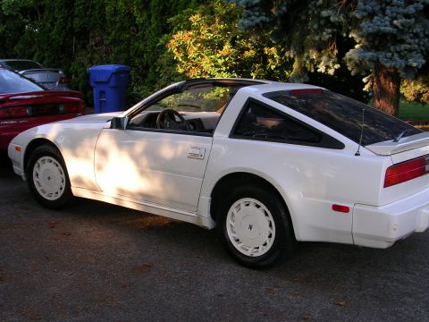 1989 Nissan 300ZX - A white 1989 Nissan 300ZX is parked next to a red car and a blue trash bin.