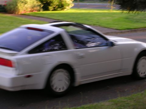 1989 Nissan 300ZX - A white 1989 Nissan 300ZX is captured in motion on a suburban street.