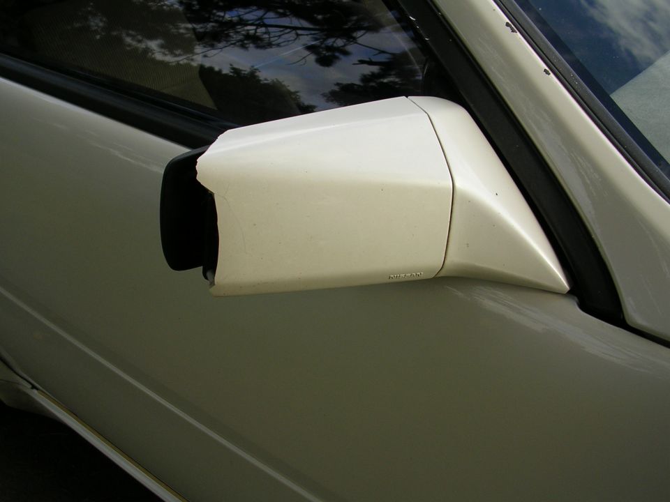 Cream side mirror with 'Nissan' text visible