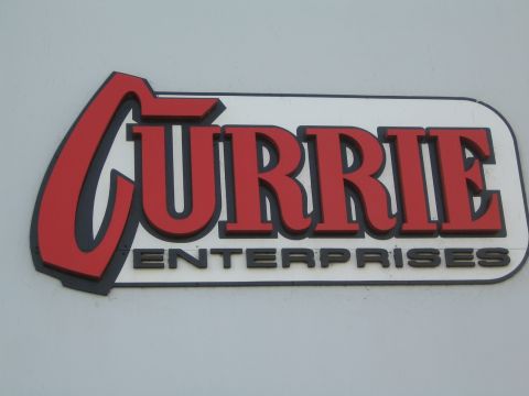 1990 Ford Bronco - close-up of the red and black Currie Enterprises logo mounted on a light-colored wall.