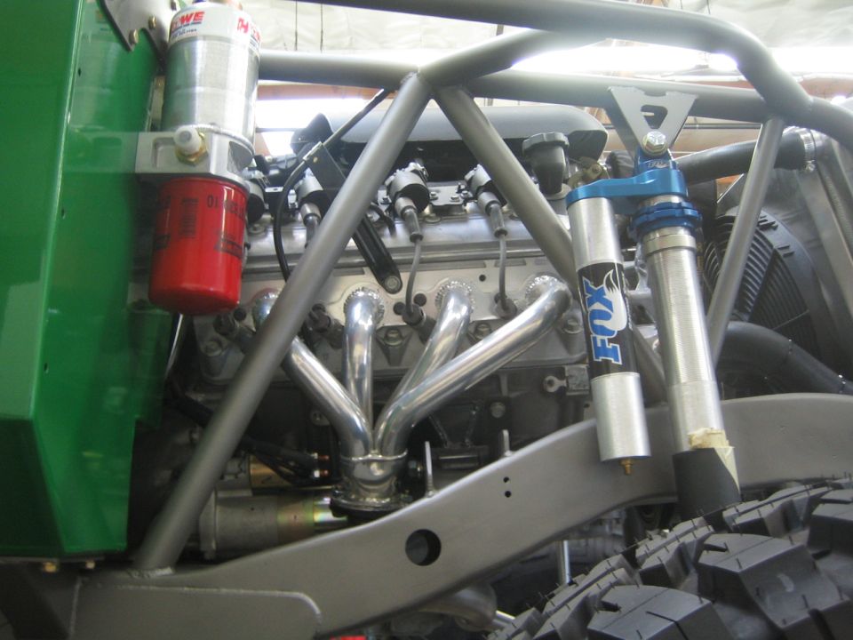Engine bay detail of green buggy with chrome headers and blue Fox shock