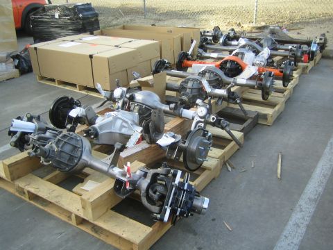 1990 Ford Bronco - Several fully assembled vehicle axles with brakes and differentials staged on wooden crates in an outdoor yard.