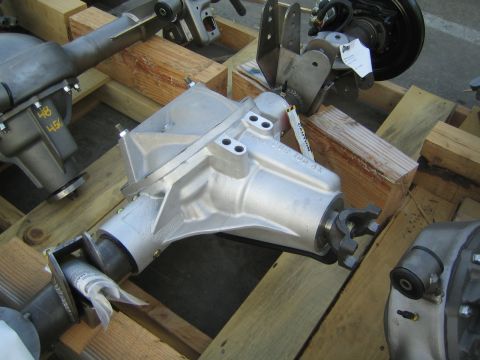 1990 Ford Bronco - cast differential center section and related axle housing parts staged on wooden crates outdoors.