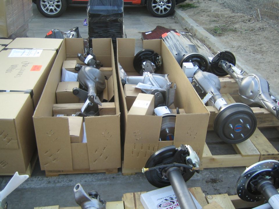 Differential parts in cardboard boxes beside assembled axles outdoors