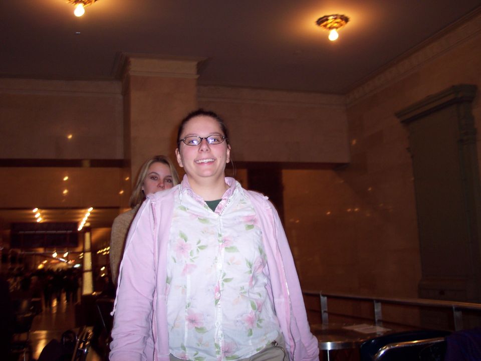 Two women indoors, one in foreground wearing glasses and a floral shirt