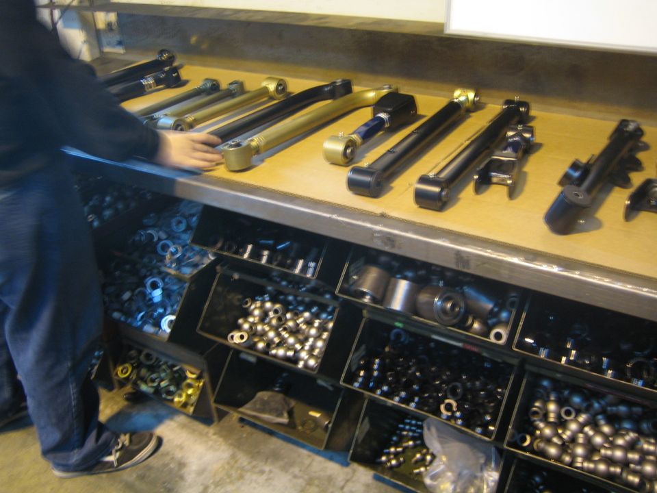 Person at workbench with suspension arms above bins of parts and hardware