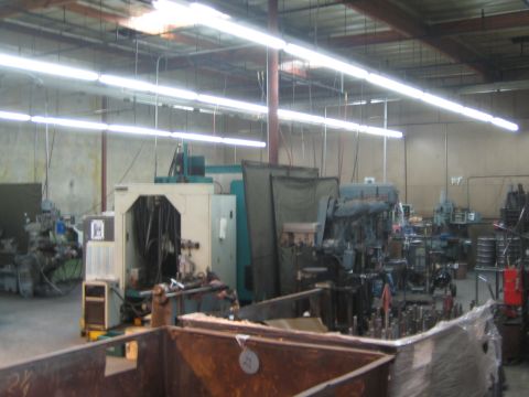 1990 Ford Bronco - wide view of a fabrication machine shop interior showing milling equipment, scrap bins and overhead lighting.